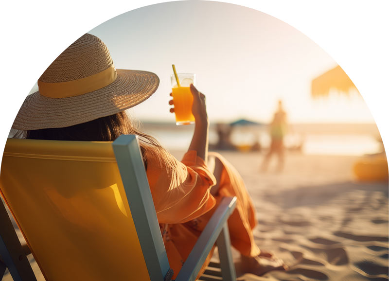 A woman relaxing in a beach chair holding a class with an orange beverate
