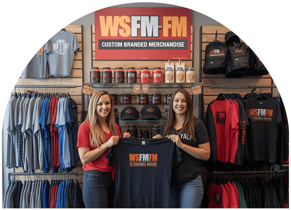 Two women holding a logo'd shirt