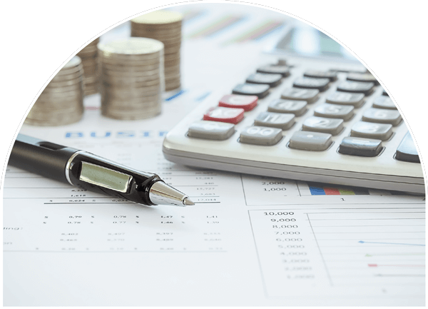 Stacked silver coins on an office desk with an ink pen and calcuator